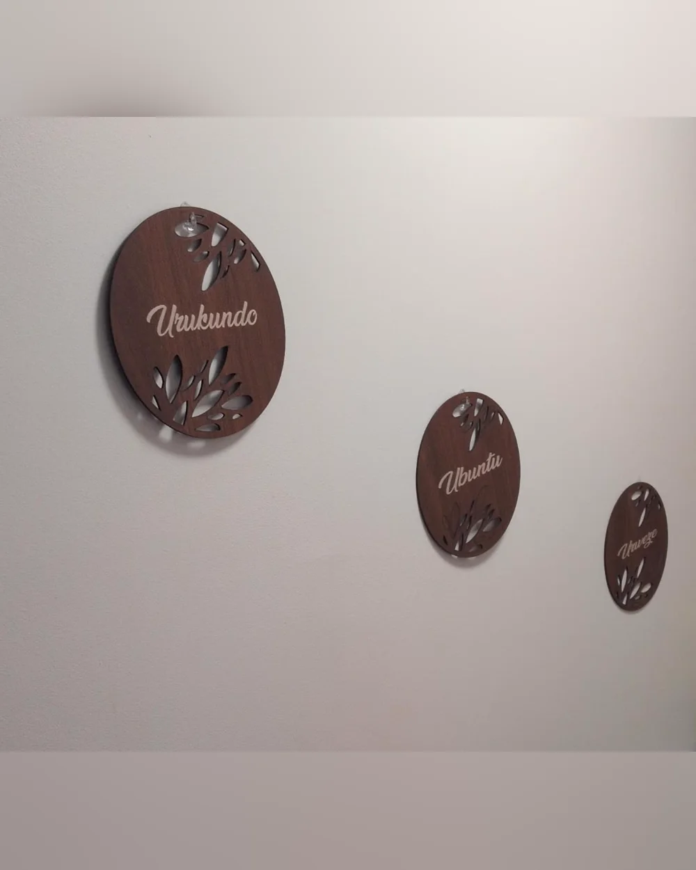Trois grands mots accrochés en diagonale sur un mur blanc : Urukundo, Ubuntu, Urweze